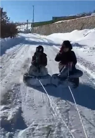 Elazığ’da otomobil lastiklerini kızak gibi kullanan çocuklar, aracın arkasına bağlanan